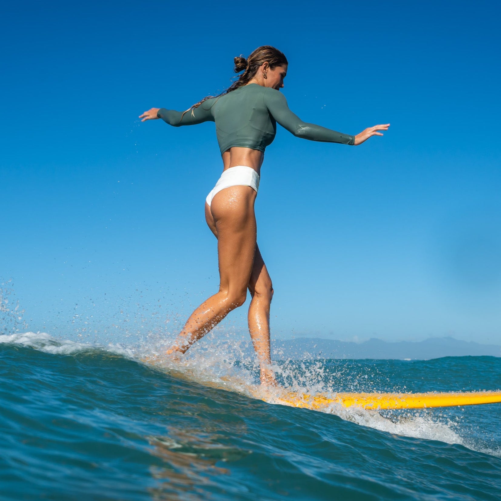 Woman surfing on a wave with a clear blue sky