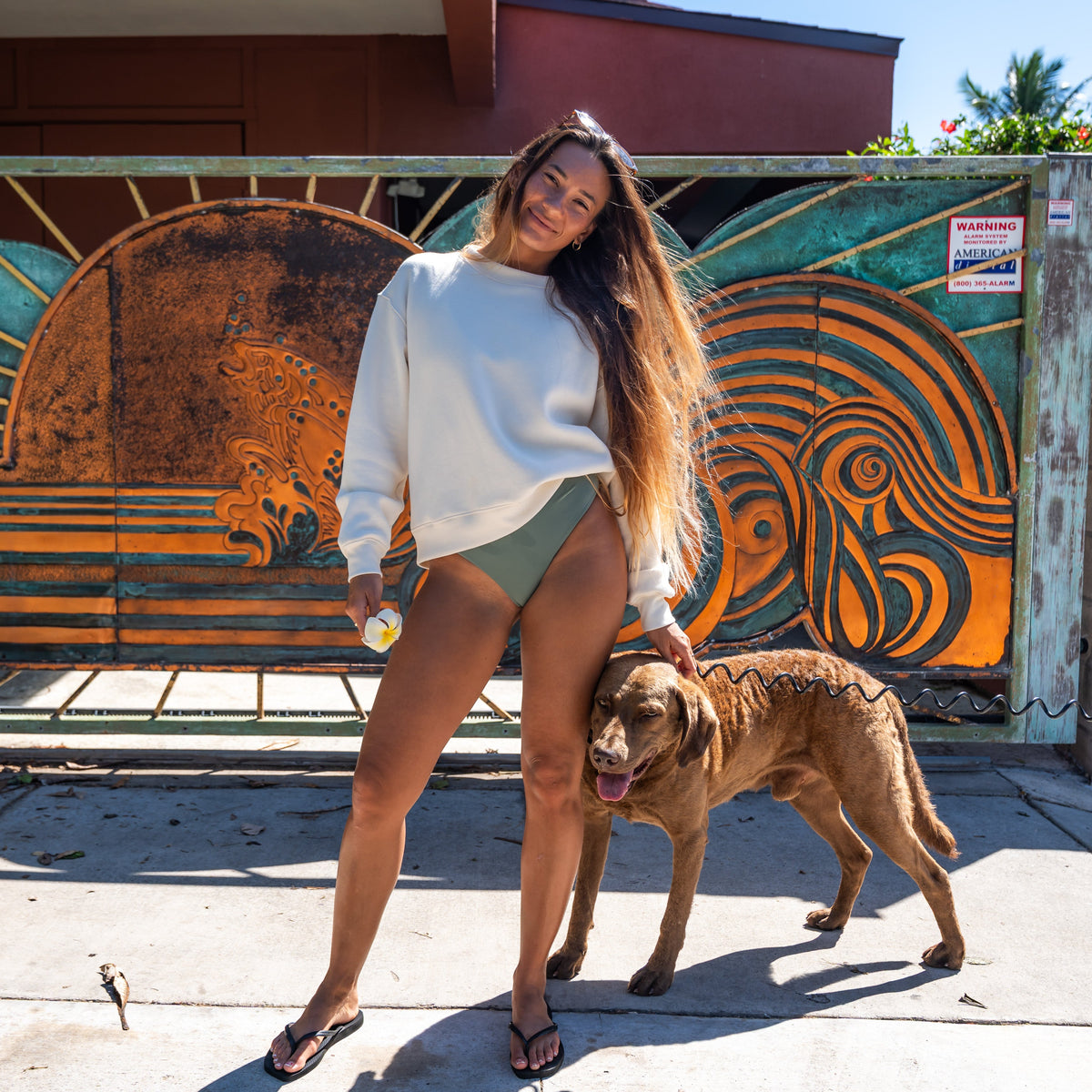 Woman standing with a dog in front of a colorful mural on a wall.