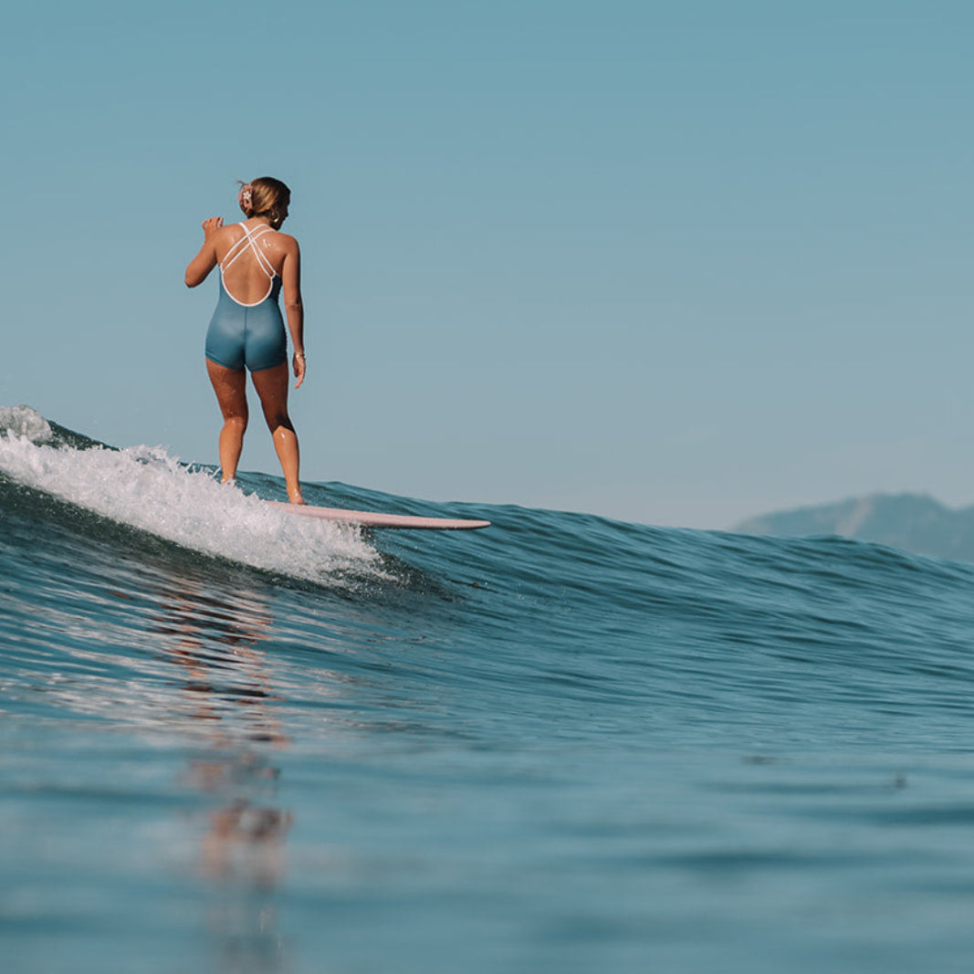 Person surfing on a wave with mountains in the background