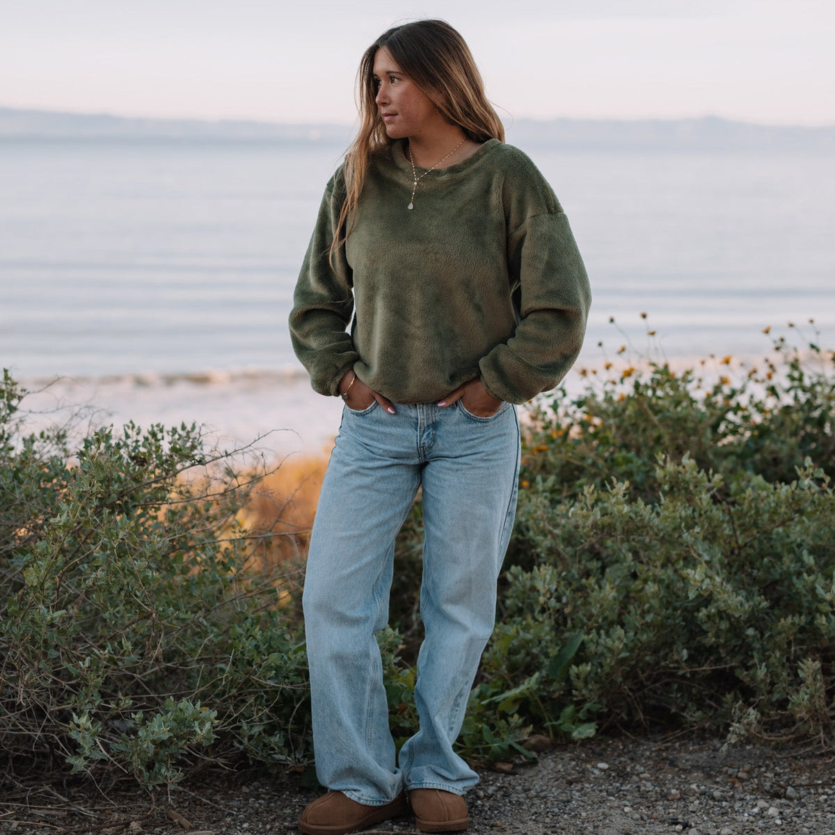 Person standing by a coastal area with ocean and sky in the background