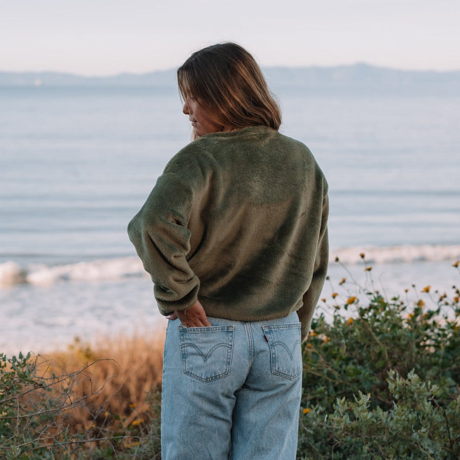 Person standing by a body of water, looking out towards the horizon.