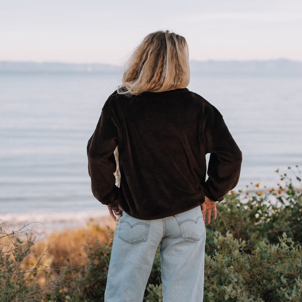 Person standing by a body of water with mountains in the distance