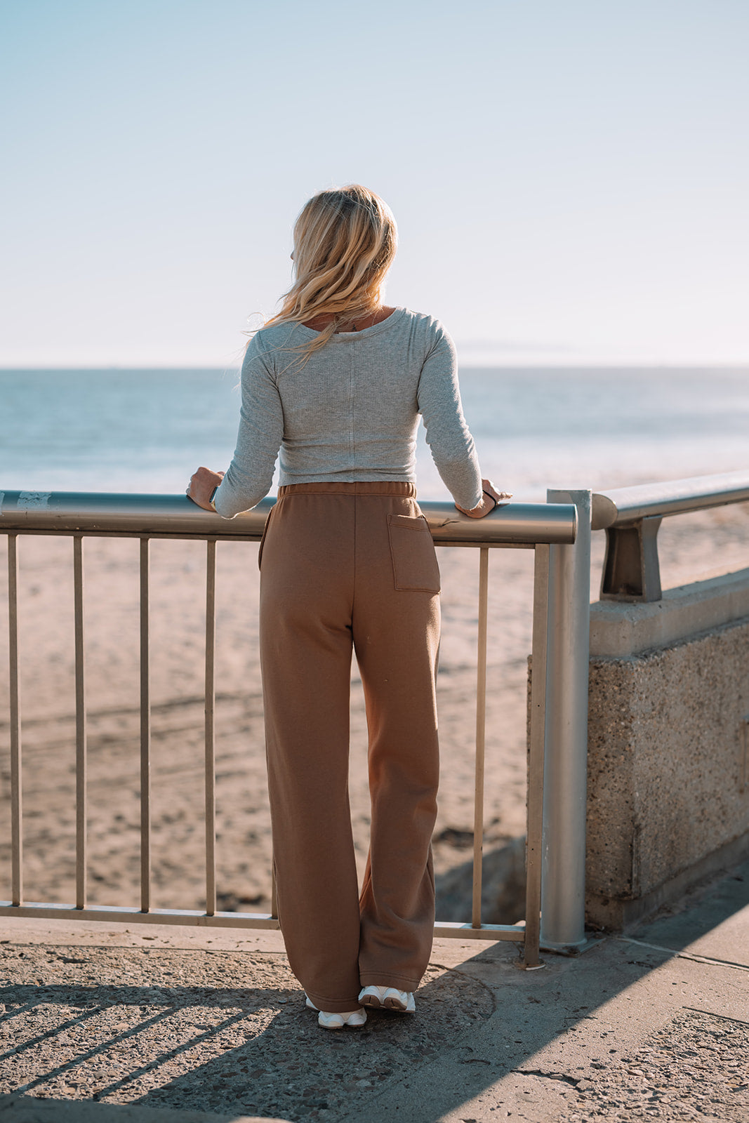 Woman standing on a balcony overlooking the ocean.