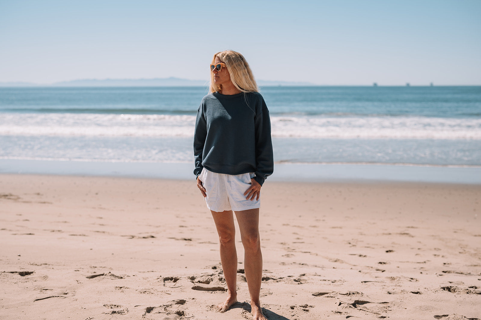 Woman standing on a beach with ocean waves in the background