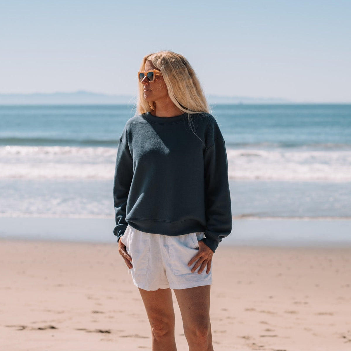 Woman standing on a beach with ocean waves in the background