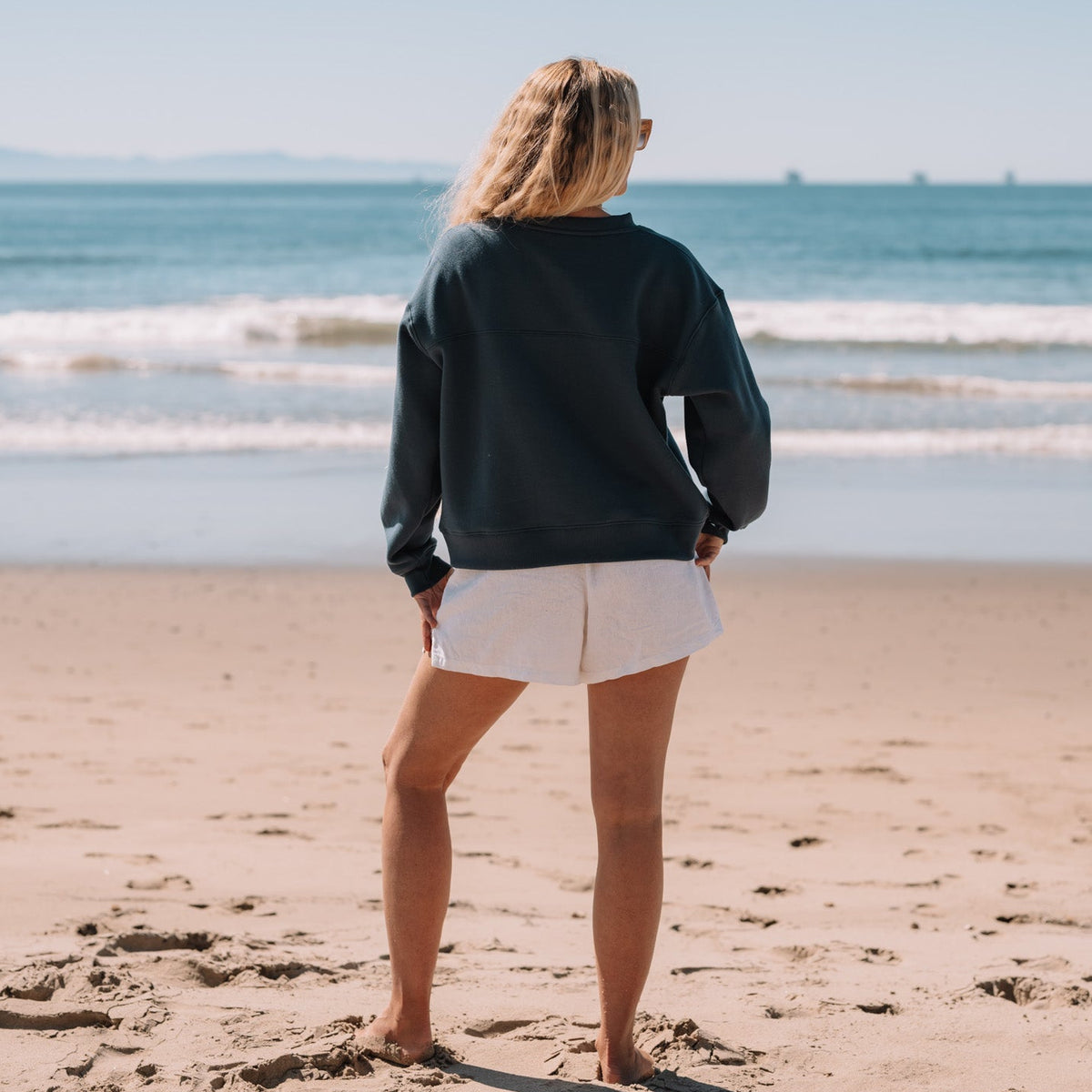 Person standing on a beach looking at the ocean