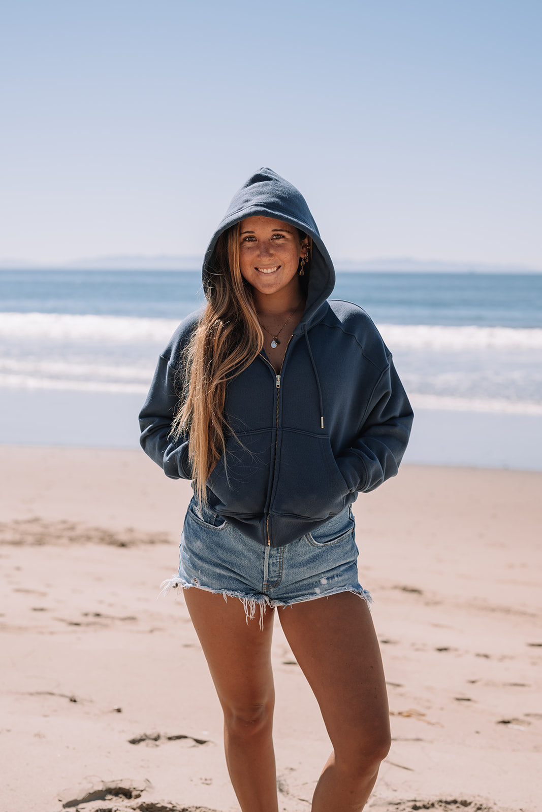 Girl in blue hoodie smiling at camera.