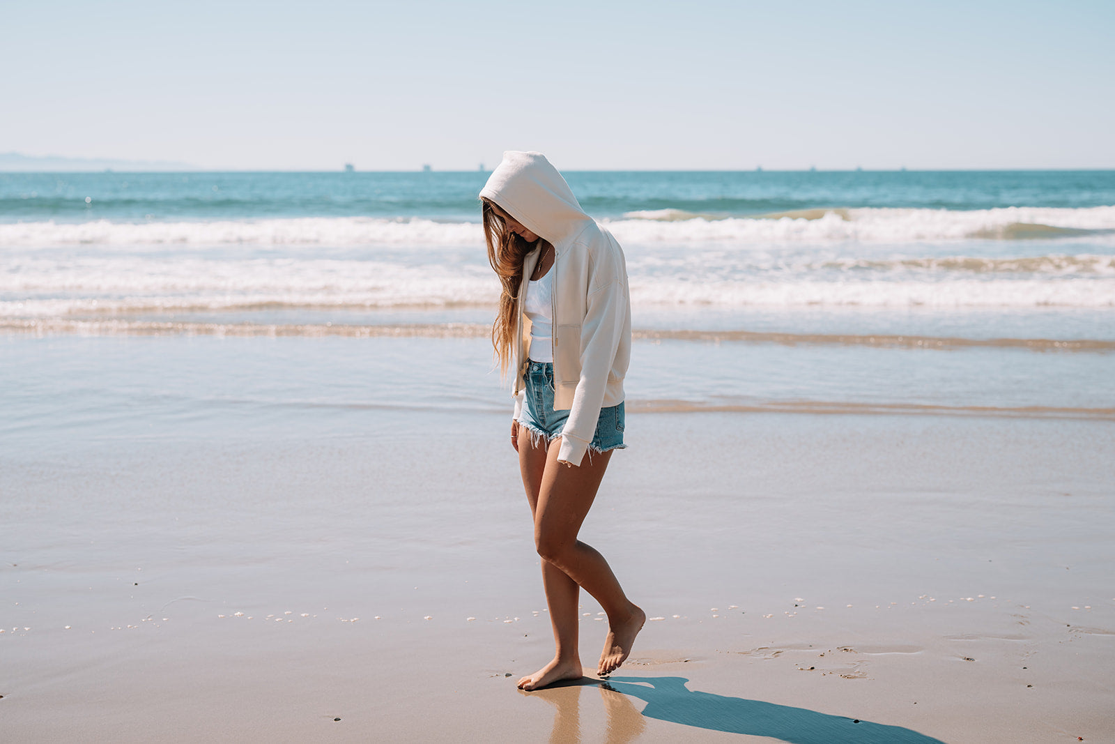 Person walking on a beach with ocean waves in the background