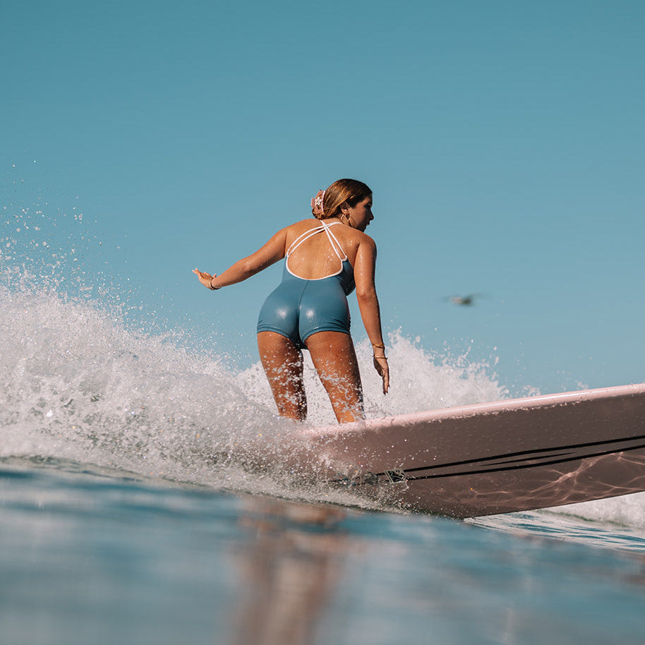 Person surfing on a wave with clear blue sky