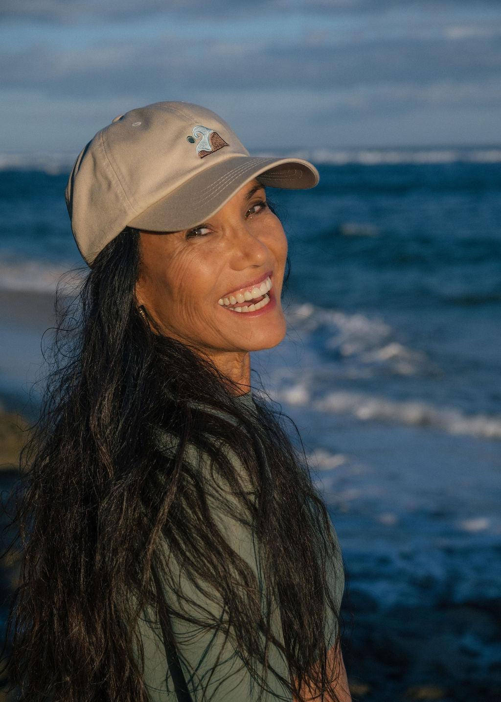 Woman smiling back at camera wearing a Coastal Range hat and green top