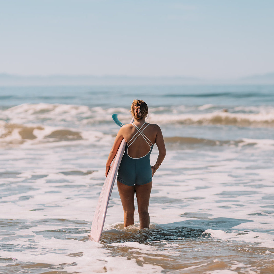 Woman holding a surfboard standing in shallow water at the beach
