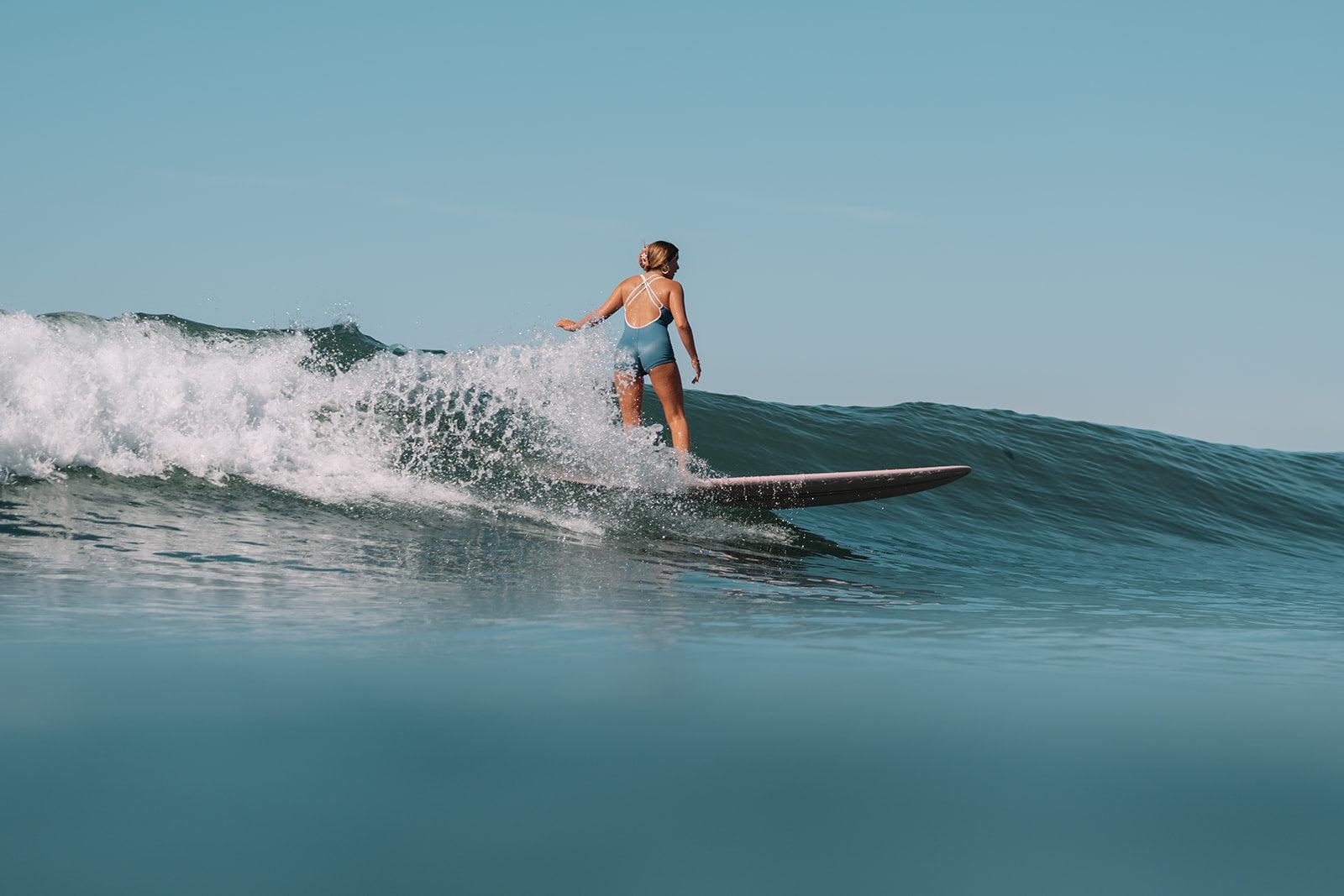 Person surfing on a wave with clear blue sky