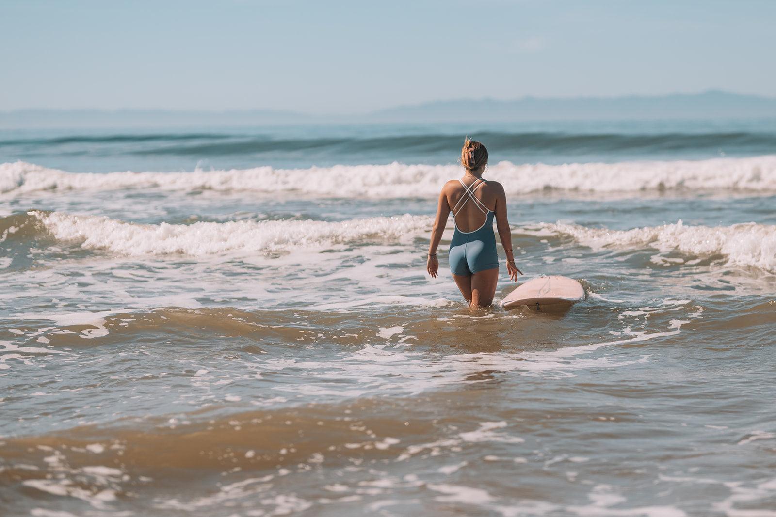 Person walking into the ocean with a surfboard