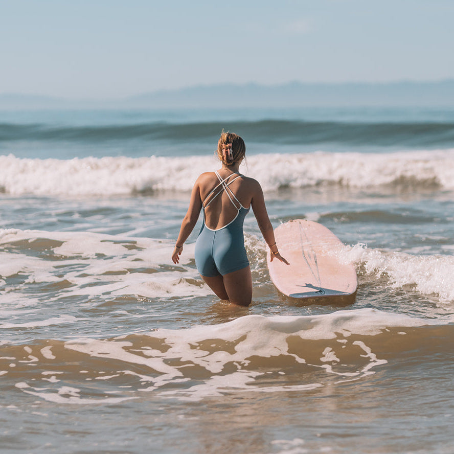 Person holding a pink surfboard in the ocean