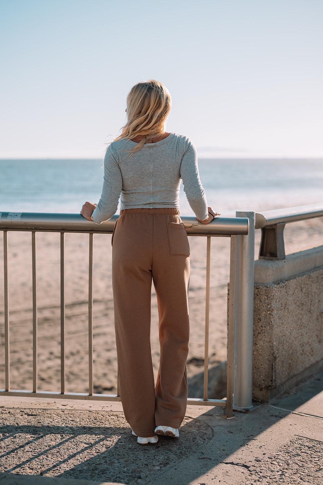 Woman standing on a balcony overlooking the ocean.