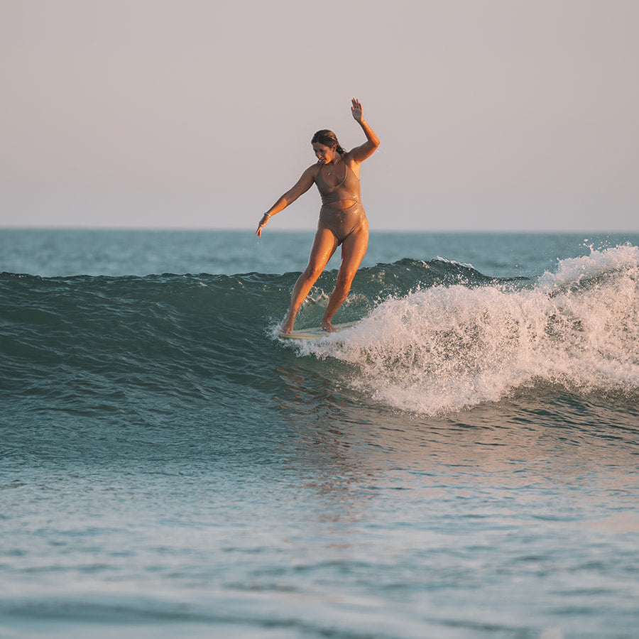 Person surfing on a wave in the ocean with a clear sky.