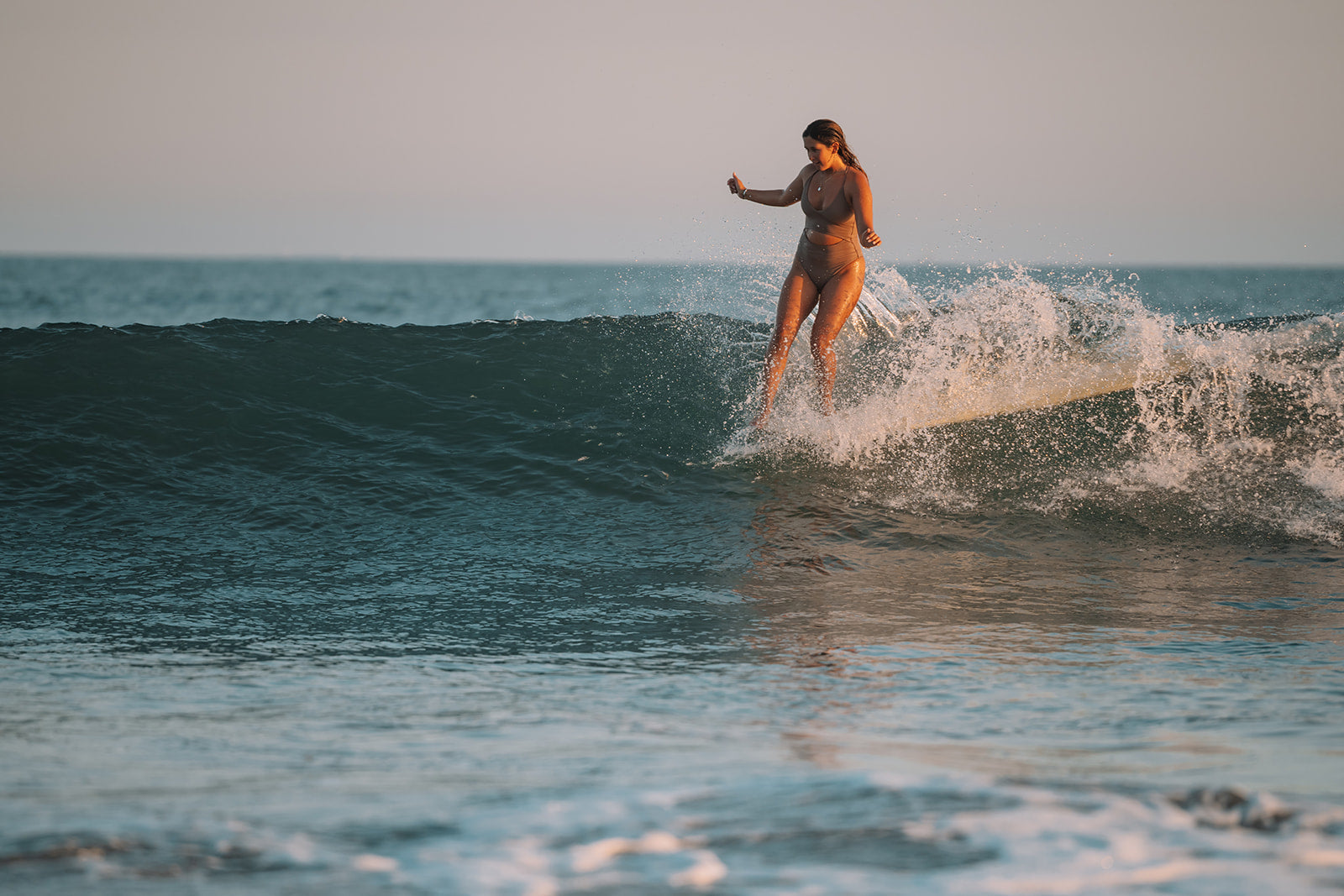 Foiling at sunset over ocean, sustainable swimwear